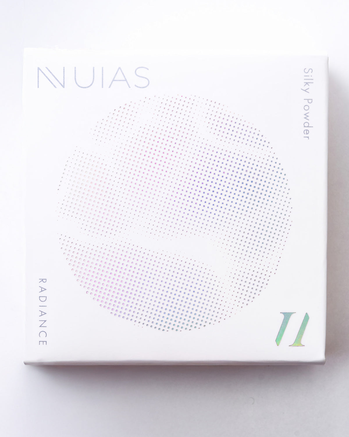 白地にホログラム風の「NUIAS」ロゴと円形ドットグラフィックが施された、ラディアンス シルキーパウダーの外箱正面画像 メイン画像