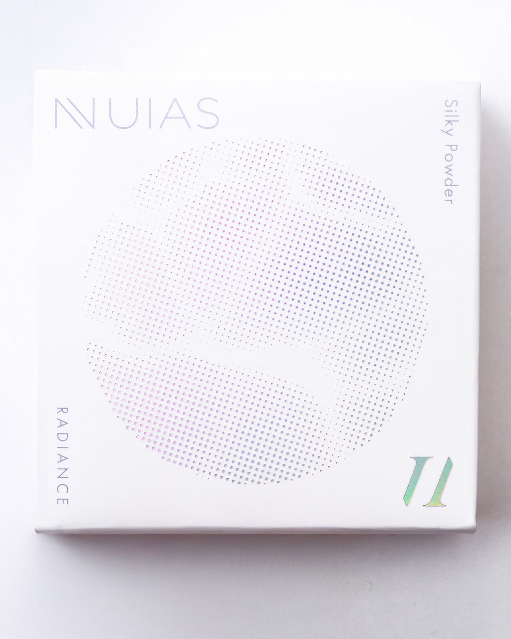 白地にホログラム風の「NUIAS」ロゴと円形ドットグラフィックが施された、ラディアンス シルキーパウダーの外箱正面画像